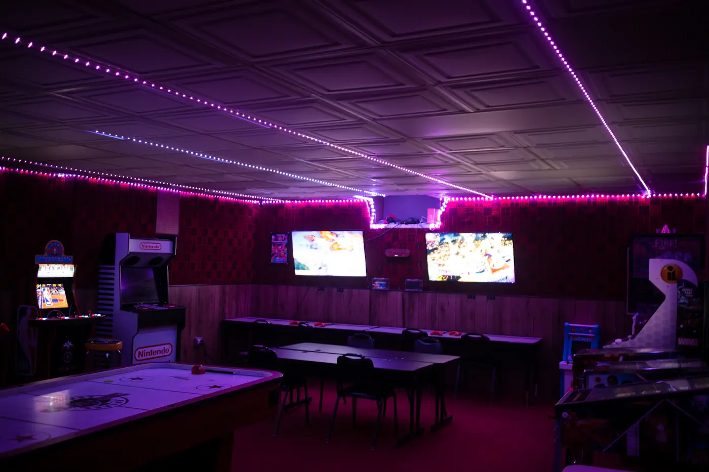 Sala con tavoli, videogiochi e luci al neon